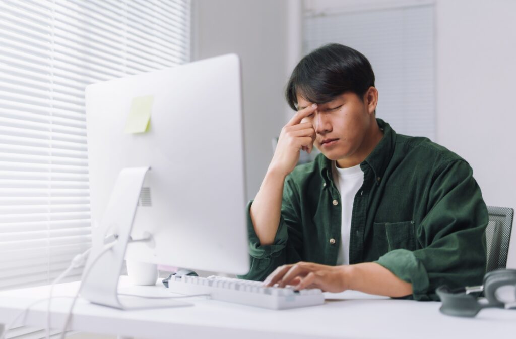 A person rubbing in between their eyes to sooth the irritation they are experiencing from dry eye